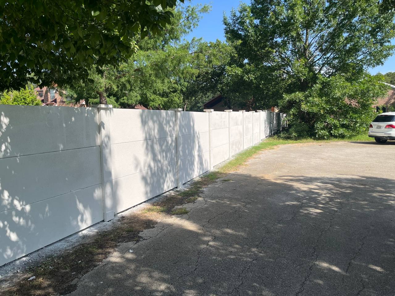 Long run of white precast concrete fence panels along a drive
